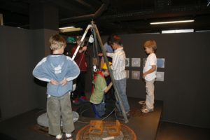 Kinder stehen in einem dunklen Ausstellungsraum
