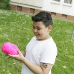Junge mit einem pinkfarbenen Wollknäuel