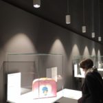 Blick in den Ausstellungsraum mit einem Objekt in einer Vitrinen und einer Person