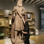 eine Frau berührt die Statue von Karl den Großen im Ausstellungsraum