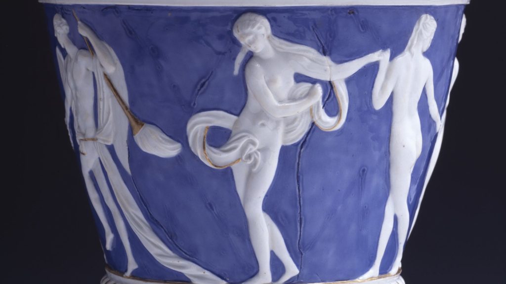 Auf dem blauen Grund des Mittelfeldes ist ein Figurenfries mit antikischen Gestalten modelliert. Zu sehen sind zwei Jünglinge vier tanzende Nymphen und zwei Putten.