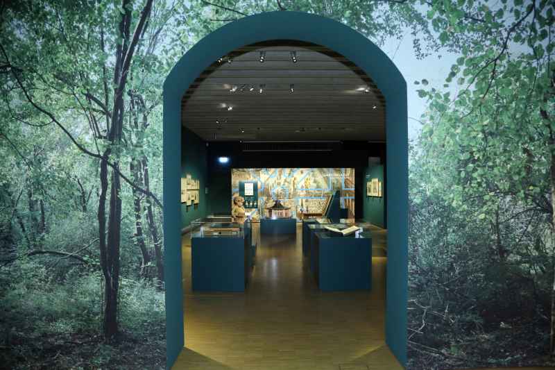 Blick in den Ausstellungsraum durch ein Tor, auf das Blätter projiziert sind