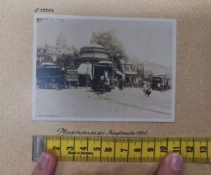 Ein Foto der Frankfurter Pferdebahn von 1895 wird vermessen. Das Maßband ist am unteren Rand des Fotos angelegt.