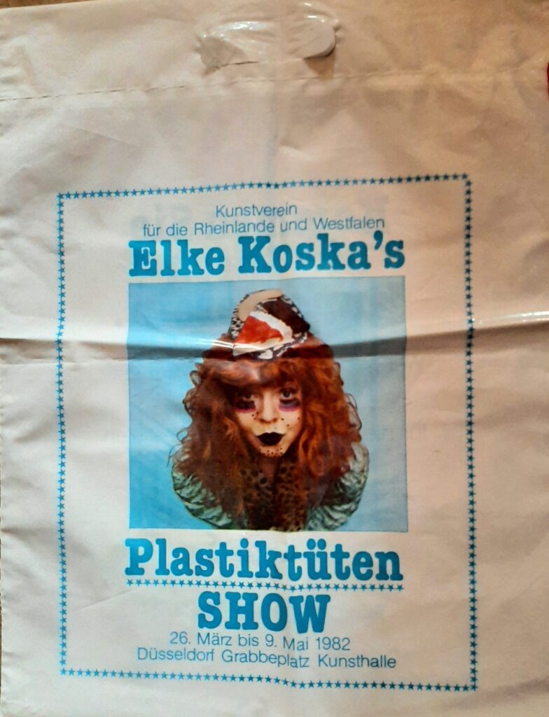 Auf einer weissen Plastiktüte ist ein gemaltes Bild von einer Frau untergebracht. darauf steht: Elke Koska's Palstiktüten Show