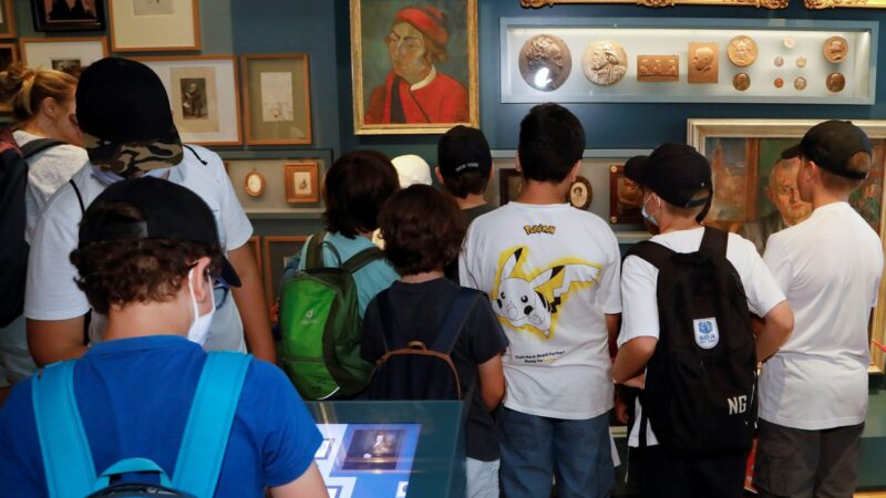 Kinder stehen vor eine Ausstellungswand mit vielen Bildern