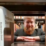 ein Mann schaut durch einen Zwischenraum von einem Bücherregal