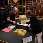 zwei menschen stehe an einem Tisch und schauen sich unterlagen an