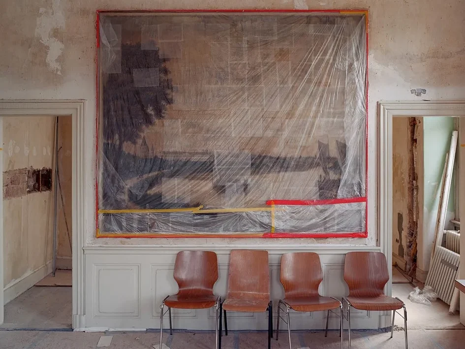 vier Stühle stehen vor einem eingepackten Bild