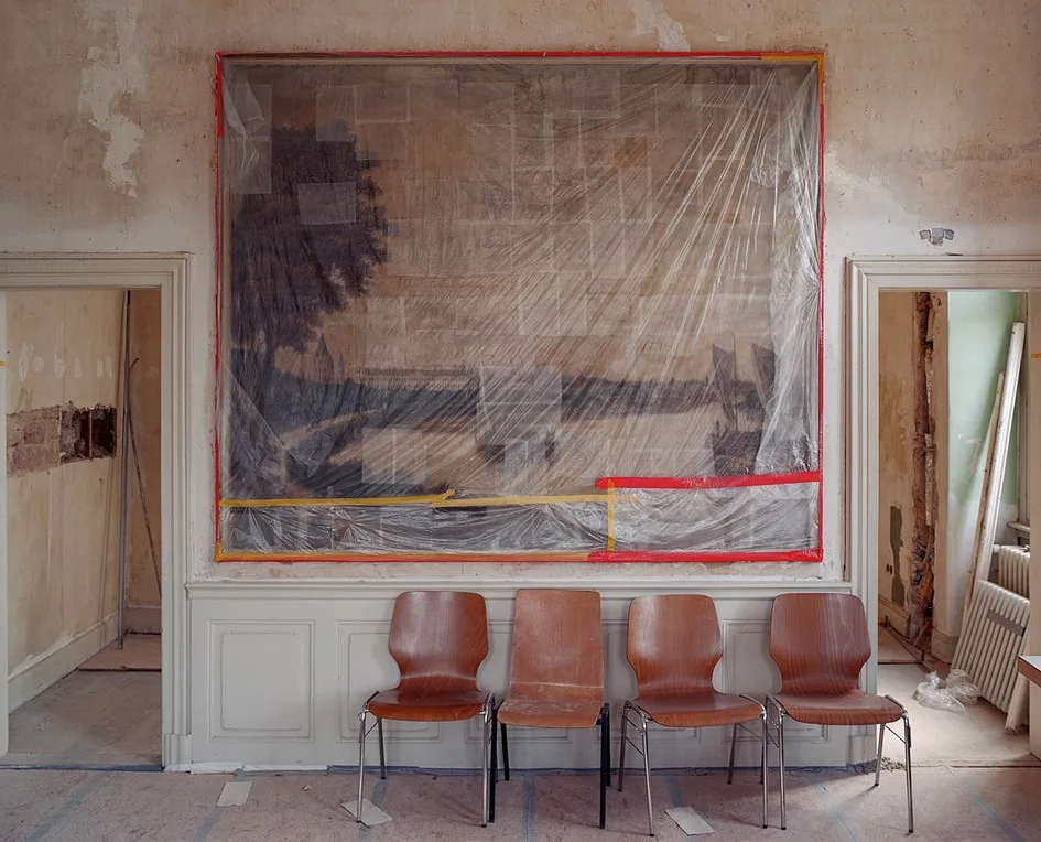 vier Stühle stehen vor einem eingepackten Bild